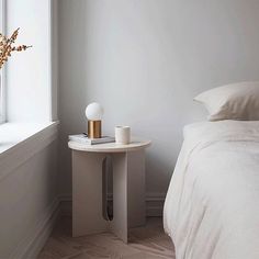 a bedroom with a bed, nightstand and vase on the table in front of the window