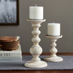 two white candles sitting on top of a table