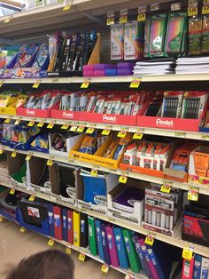 there are many books and pencils on the shelves in this store that is filled with children's crayons