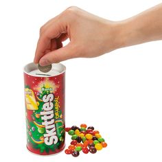 a hand is picking up a can of skittles