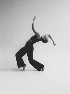 black and white photograph of a woman doing an acrobatic dance move with her hands in the air