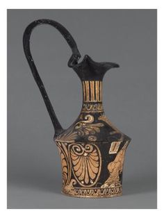 an old black and gold vase with a bird on it's top, sitting in front of a gray background