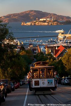 a cable car traveling down a street next to the ocean