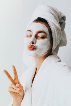 a woman in a white towel making peace sign with her hand