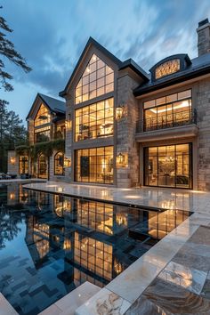 a large house with a swimming pool in the middle of it at dusk or dawn