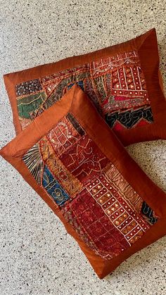 two decorative pillows sitting on top of a floor