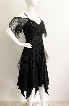 "Get ready to party in this fabulous off the shoulder dress from Nuance, made in USA.  The body of the dress is black with a floral lace overlay that has free form gold dots throughout.  The flirty hemline is handkerchief, high low style.  Each triangle section is separate, so the dress is full of movement and peaks of leg.  The bodice has spaghetti straps and off the shoulder lace \"sleeves\".  Great 80's look.  Size tag 9, check measurements carefully, no stretch.  Fits mannequin 35X26X33. Mea Summer Formal Lace Dress With Fitted Bodice, Fitted Evening Dress With Lace Sleeves For Party, Party Evening Dress With Lace Sleeves And Sweetheart Neckline, Summer Formal Lace Evening Dress, Evening Lace Dress For Party Season, Fitted Lace Dress With Ruffles For Gala, Summer Lace Evening Dress For Formal Events, Summer Lace Evening Dress For Formal Occasions, Summer Lace Dress With Fitted Bodice And Lace Sleeves