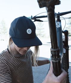 a woman wearing a hat is fixing a bicycle