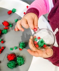 a child holding a glass jar filled with red and green pom - poms