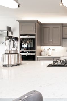 a kitchen with gray cabinets and white counter tops