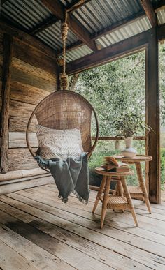 a hammock hanging from the ceiling on a porch with a table and chair