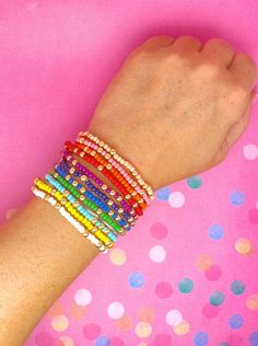 a woman's arm with colorful bracelets on it