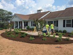 two men working on landscaping in front of a house