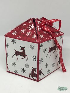 an origami box with reindeers and snowflakes on it, tied with a red ribbon