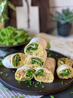 there are several wraps on the plate with lettuce and other vegetables in the background