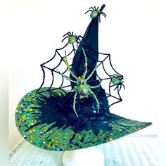 a hat with spider webs and sequins on the top is sitting on a table