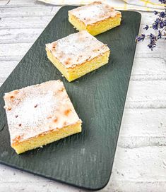 three pieces of cake sitting on top of a black plate next to lavender sprigs