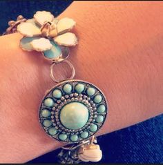 a close up of a person's arm wearing a bracelet with flowers on it