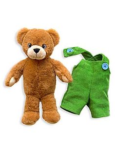 a brown teddy bear sitting next to a green onesie on a white surface,