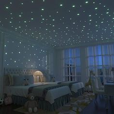 a bedroom with stars on the ceiling and two twin beds in front of large windows