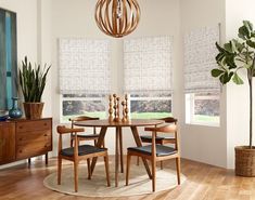 a dining room table with four chairs and a potted plant in the corner next to it