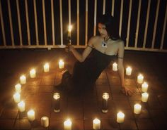 a woman sitting on the ground surrounded by candles