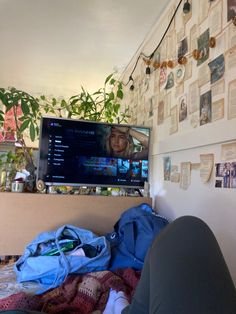 a flat screen tv sitting on top of a wooden dresser next to a wall covered in pictures