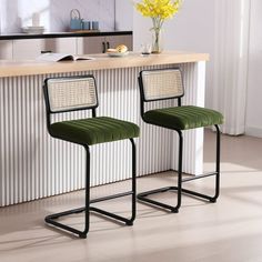 two green chairs sitting next to each other in front of a counter top with flowers on it