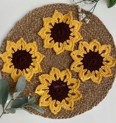 four crocheted sunflowers sitting on top of a brown and yellow mat