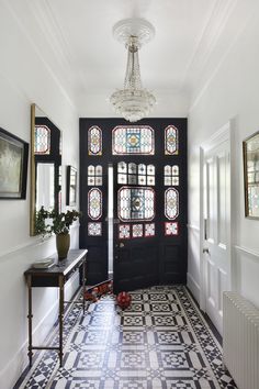 a black door with stained glass windows in a hallway next to a table and bench