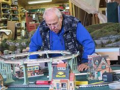 an older man looking at a model train set