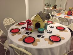 there is a dog house on the table with red plates and placemats around it