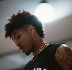 a close up of a person wearing a black shirt with tattoos on his arms and shoulder