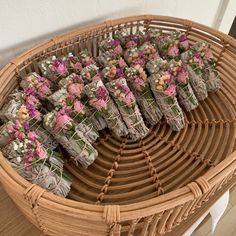 several bundles of dried flowers sitting in a wicker basket on top of a wooden table