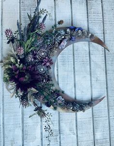 a flower arrangement is placed on top of a crescent shaped wreath that sits on a wooden surface