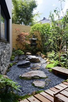 a small garden with rocks, plants and water features in the back side of the house