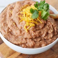 a white bowl filled with oatmeal topped with cheese and cilantro