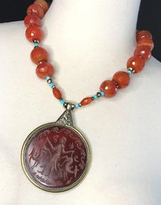 Vintage Afghan Pendant Necklace This One of a Kind Statement Necklace is assembled by me. I collected this incredible genuine Carnelian Intaglio pendant on my recent travels. The pendant is encased in brass with a silver rope design and lovely ornate metal backside of the pendant.  This style of carved Carnelian is associated with Bactria, once part of the Persian Empire. Carnelian has always been considered a lucky talisman throughout ancient history and is still popular today. Red Carnelian is Round Carved Agate Necklaces, Carved Agate Round Necklaces, Bohemian Carnelian Cabochon Jewelry, Unique Round Carnelian Jewelry, Antique Carnelian Necklace For Gift, Antique Style Necklaces With Natural Stones, Antique Gemstone Beaded Jewelry, Carnelian Cabochon Necklaces For Jewelry Making, Antique Round Gemstone Beads Jewelry