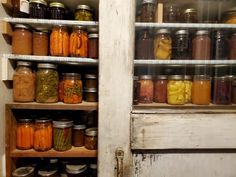 jars filled with pickles and other vegetables sit on shelves in an old door way