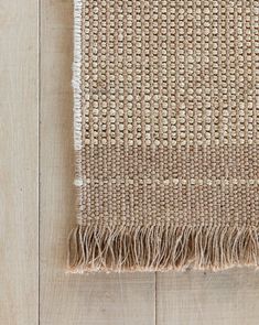 an area rug with fringes on top of wooden flooring next to a wall