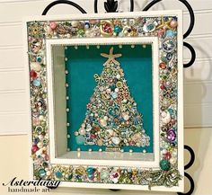 a christmas tree made out of buttons and other items in a frame on a table