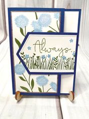 a card with blue flowers and the words always on it, sitting on a wooden stand