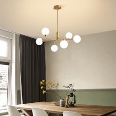 a dining room table with white chairs and a light fixture hanging from it's ceiling