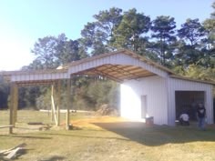 two people are standing in the open door of a building that is white and has a metal roof