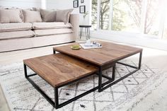 two coffee tables sitting on top of a rug in front of a couch and window