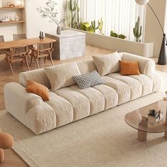 a living room filled with lots of furniture and plants on top of the floor next to a window