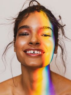 a woman is smiling with her face painted multicolored