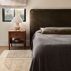 a bedroom with a bed, night stand and lamp on the side table in front of it