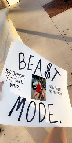 a person holding up a sign that says beast mode