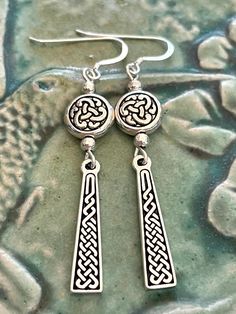 "Celtic knot dangle earrings. These beautiful hand cast Celtic earrings are lightweight and striking. They have intricate Celtic knot symbols and the bottom pieces are the Ailm symbol. The Ailm is derived from the letter \"A\" of the Celtic Ogham alphabet. Ailm represents strength, endurance and resilience. The word \"Ailm\" is assumed to mean \"conifer/silver fir\". In tree lore, evergreen conifers are associated with healing one's soul. These earrings are 2 inches long and a third of an inch w Celtic Ogham, Ogham Alphabet, Irish Earrings, Celtic Knot Jewelry, Silver Fir, Celtic Knot Earrings, Knot Jewelry, Design Butterfly, Celtic Earrings